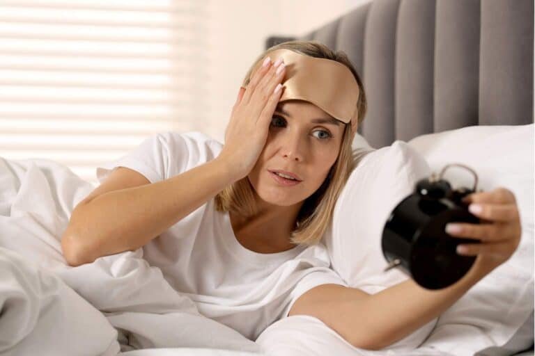 femme fatiguée regardant son réveil le matin
