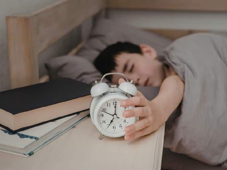 enfant fatigué éteignant un réveil bruyant le matin