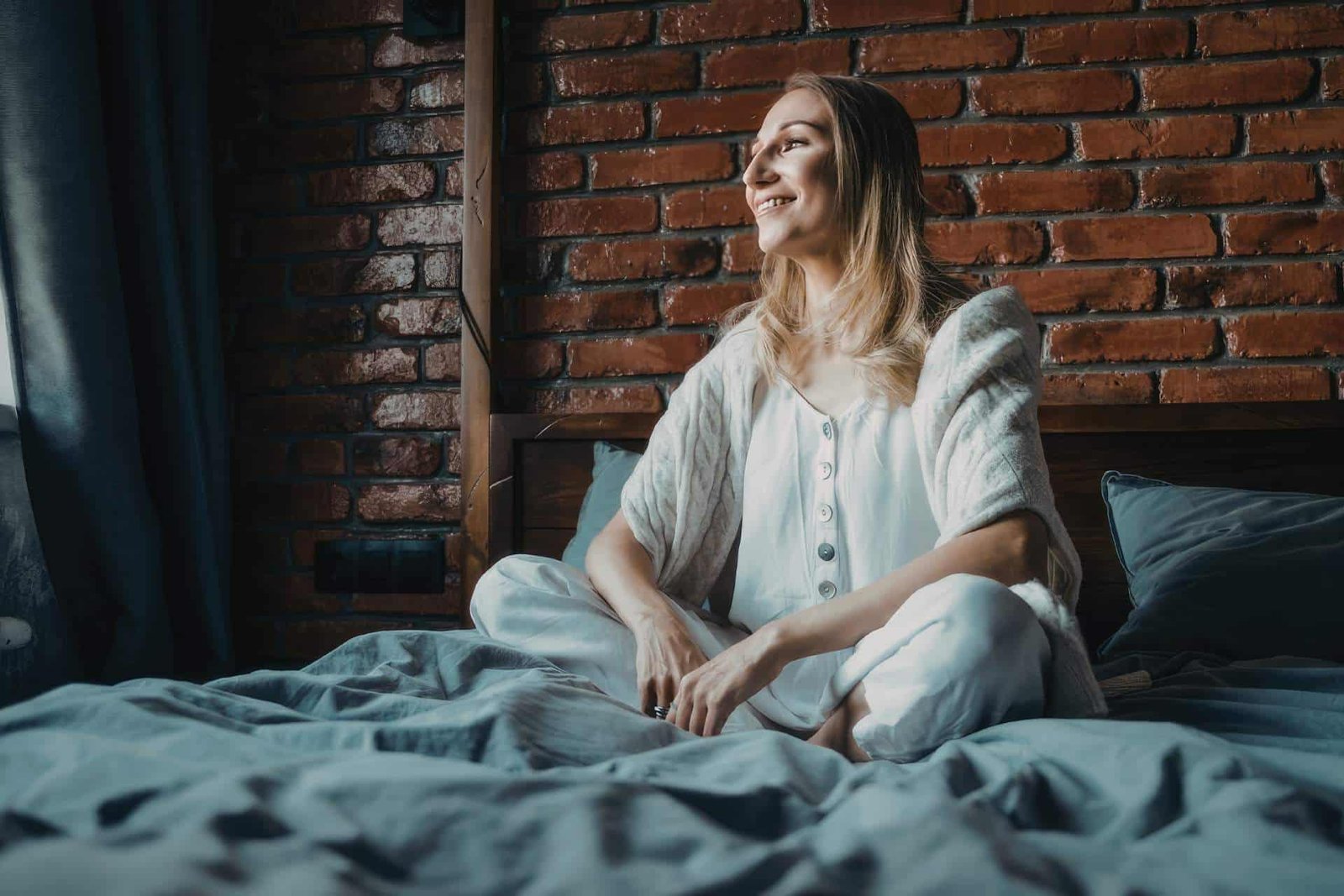 femme se réveillant calmement et souriante dans son lit